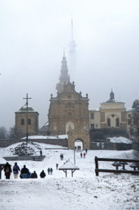 Klasztor Misjonarzy Oblatów na Świętym Krzyżu w zimowej scenerii w tle majaczy spowity mgłą nadajnik wieży telewizyjnej