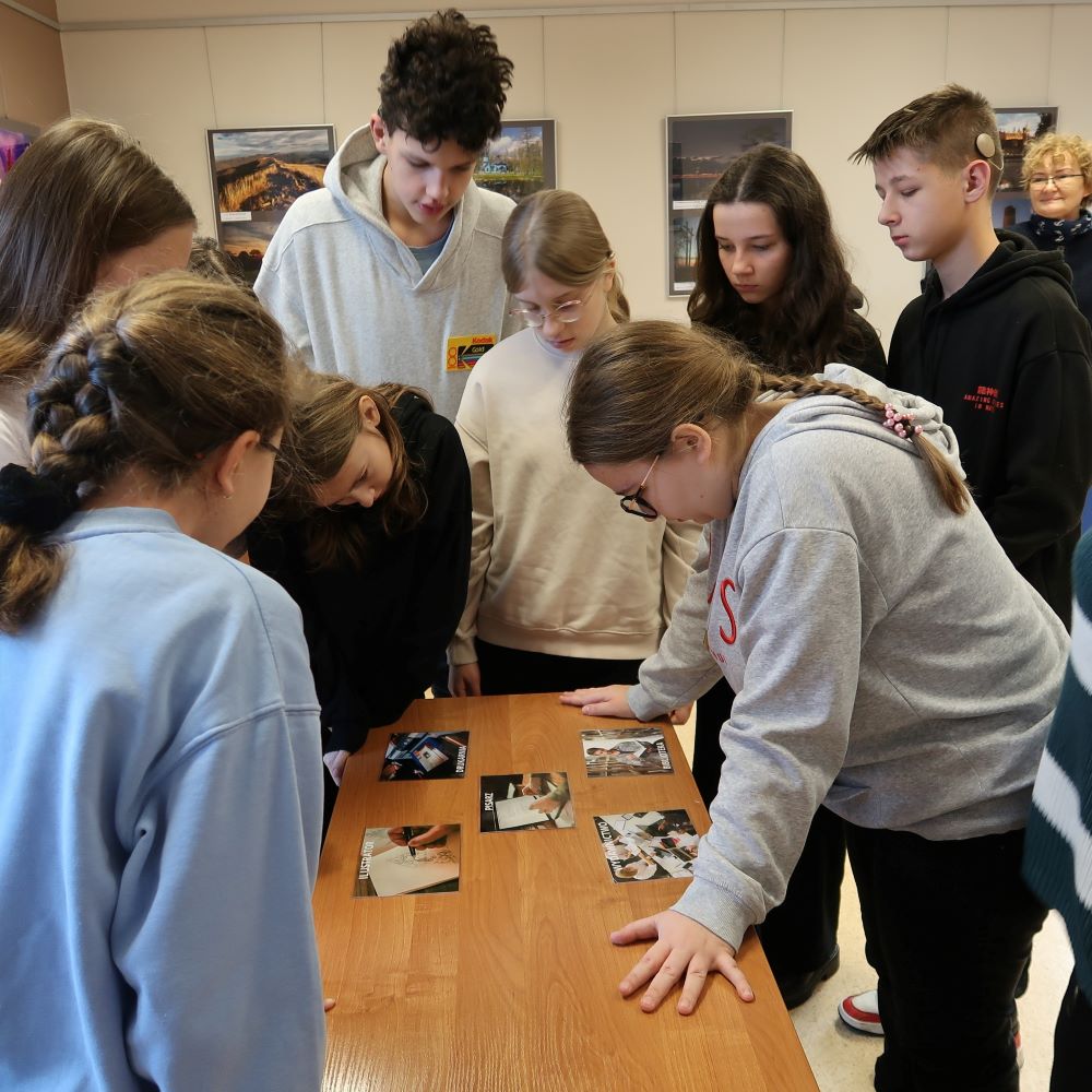 Grupa ludzi oglądających zdjęcia na stole.