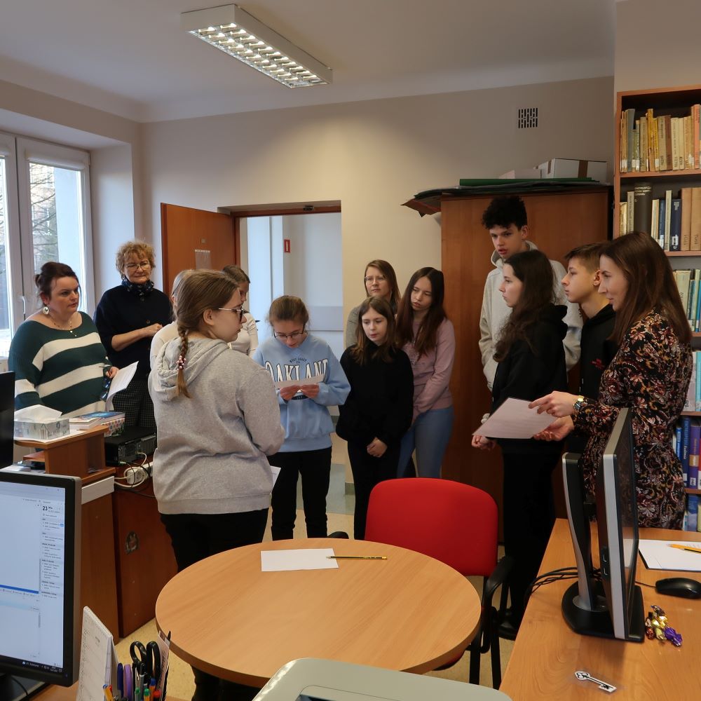Grupa ludzi stojących wokół biurka w bibliotece.