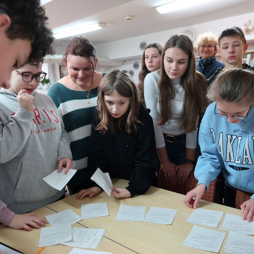 Grupa ludzi stojących wokół stołu.