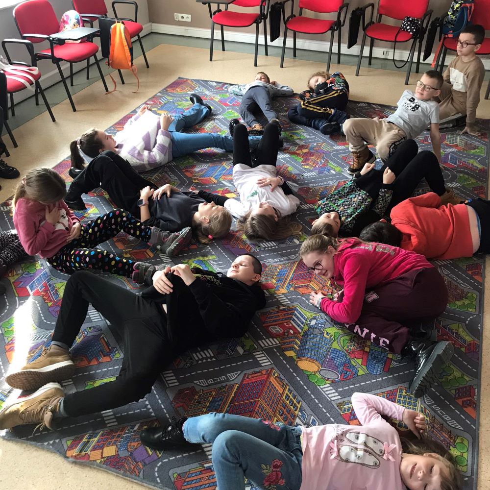 Grupa dzieci leżących na podłodze w pokoju.