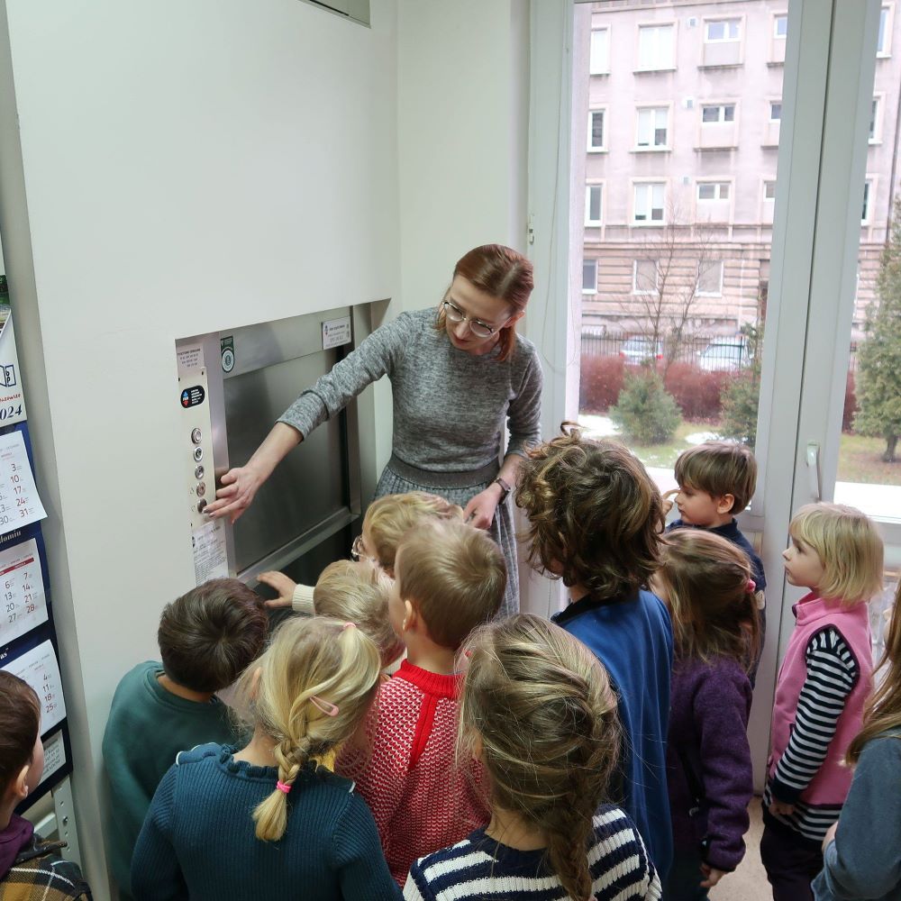 Grupa dzieci stojących przy windzie.