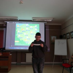 miedzynarodowy-dzien-jezyka-ojczystego-psp-24-3 Uczeń odczytuje z kartki tekst stojąc na tle mapy pogodowej Polski.