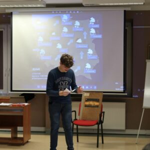 obchodody-Międzynarodowego-Dnia-Jezyka-Ojczystego-uczniowie-PSP im. Jana-Kochanowskiego-w-Zakrzewie-4 Uczeń prezentuje kalambury stojąc na tle mapy pogodowej Polski