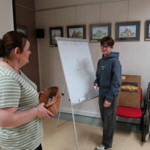 obchodody-Międzynarodowego-Dnia-Jezyka-Ojczystego-uczniowie-PSP im. Jana-Kochanowskiego-w-Zakrzewie-6 Uczeń stojąc przy tablicy rysuje kalambury