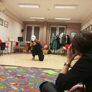 Kobieta w masce na twarzy odgrywa scenę.