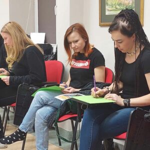 Siedzące kobiety na krzesłach robą rysunki