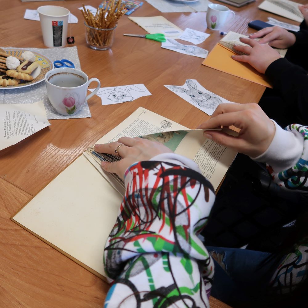 Para rąk kobiecych tworząca postać zajączka świątecznego ze starej zniszczonej książki