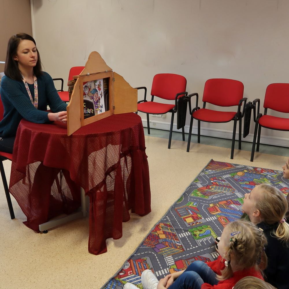 dzien-przytulania-bibliotekarza-1 Bibliotekarka opowiada dzieciom bajkę z teatrzyku kamishibai.