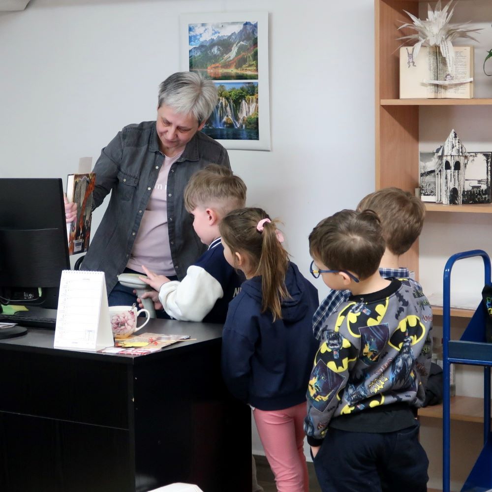 Dzieci pod kierunkiem bibliotekarki szczytują kody kreskowe książek