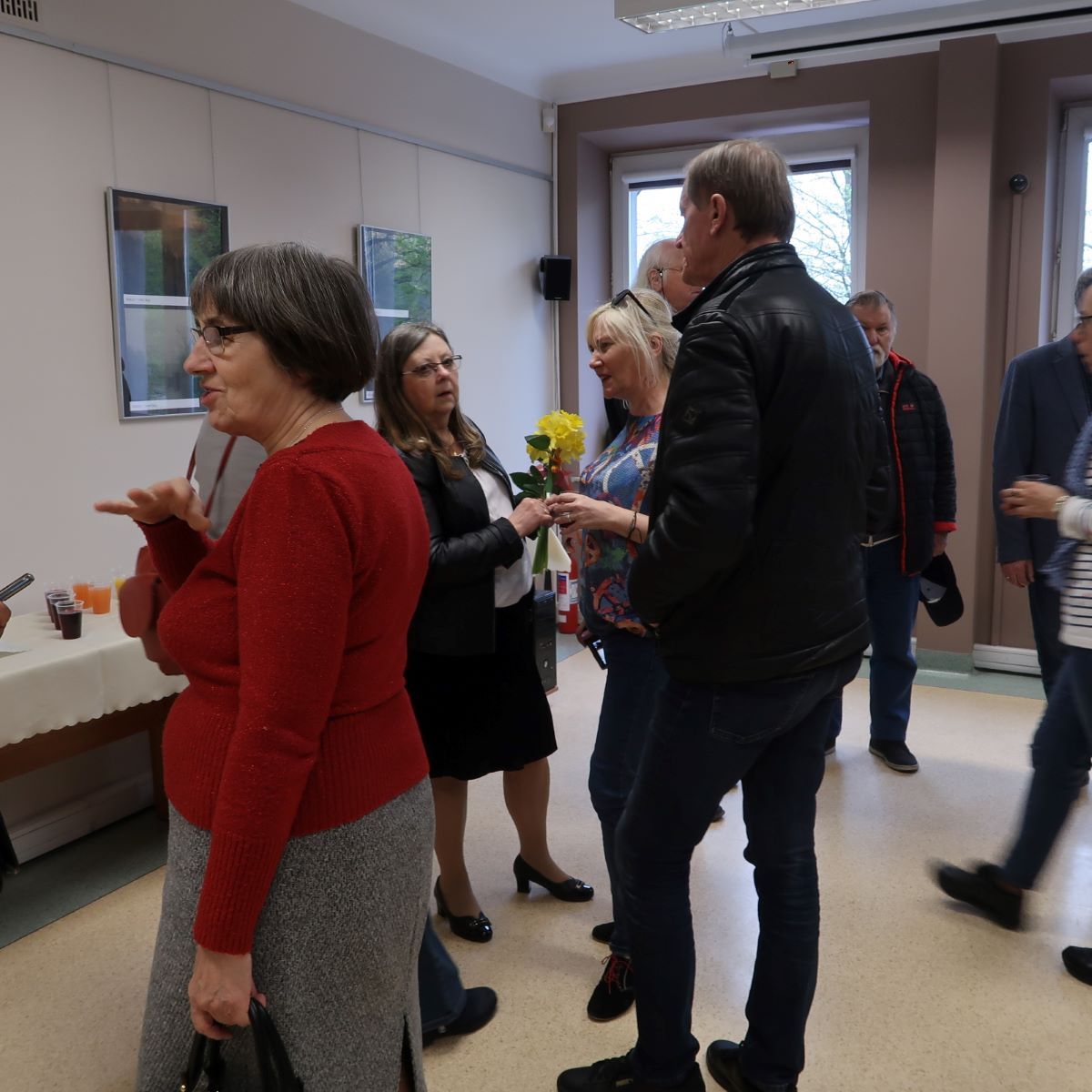 Uczestnicy wernisażu żywo dyskutują podczas oglądania prac fotograficznych