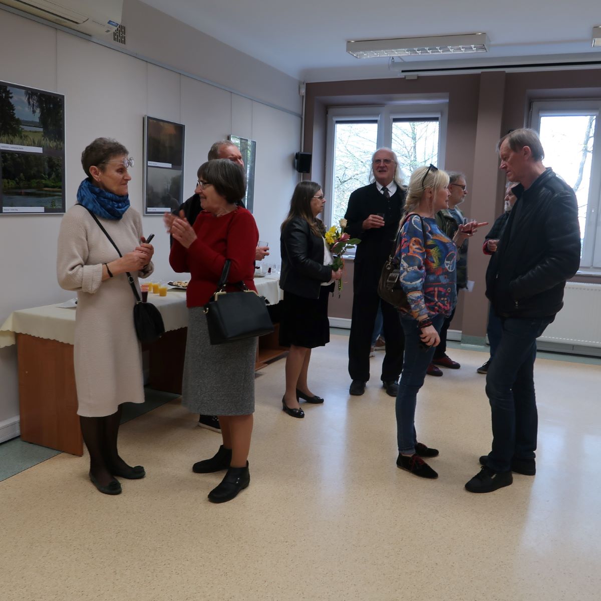 Uczestnicy wernisażu żywo dyskutują podczas oglądania prac fotograficznych