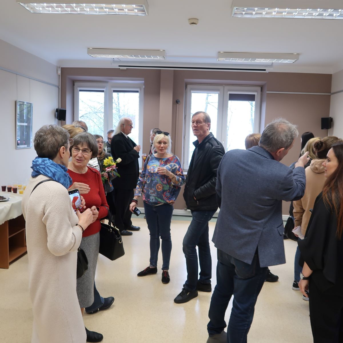 Uczestnicy wernisażu żywo dyskutują podczas oglądania prac fotograficznych