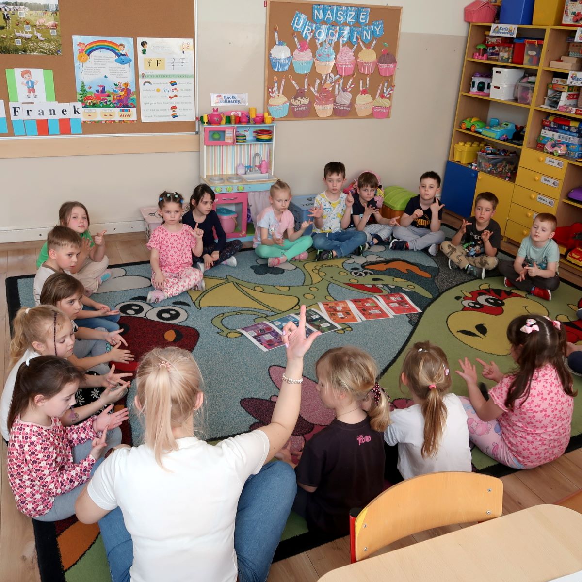 dzien-teczy-4 Dzieci w wieku przedszkolnym siedzą na dywanie w kole