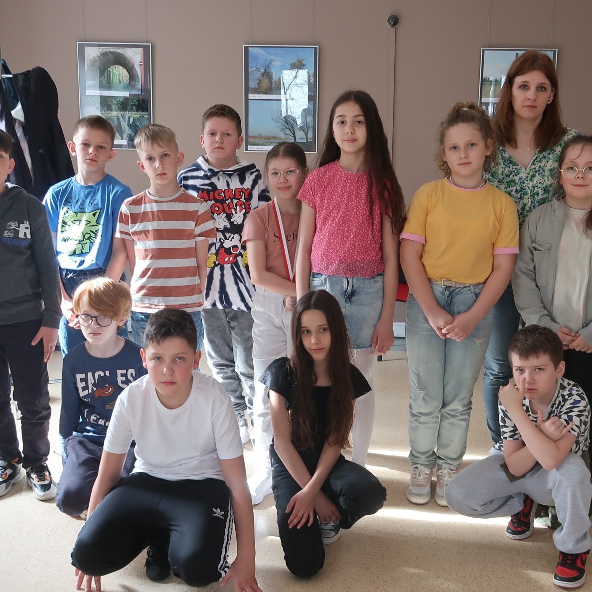 Grupa uczniów pozuje do zdjęcia pamiątkowego w sali wystawowej biblioteki