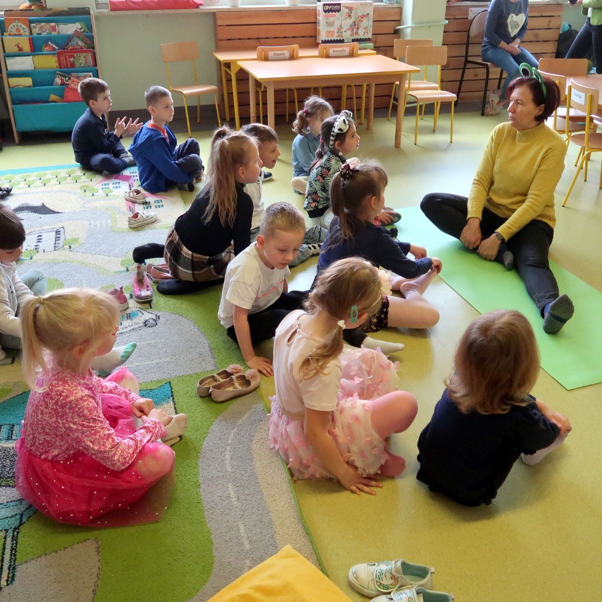 kolorowy-potwor-2 Dzieci siedząc na podłodze powtarzają ćwiczenia prezentowane przez panią