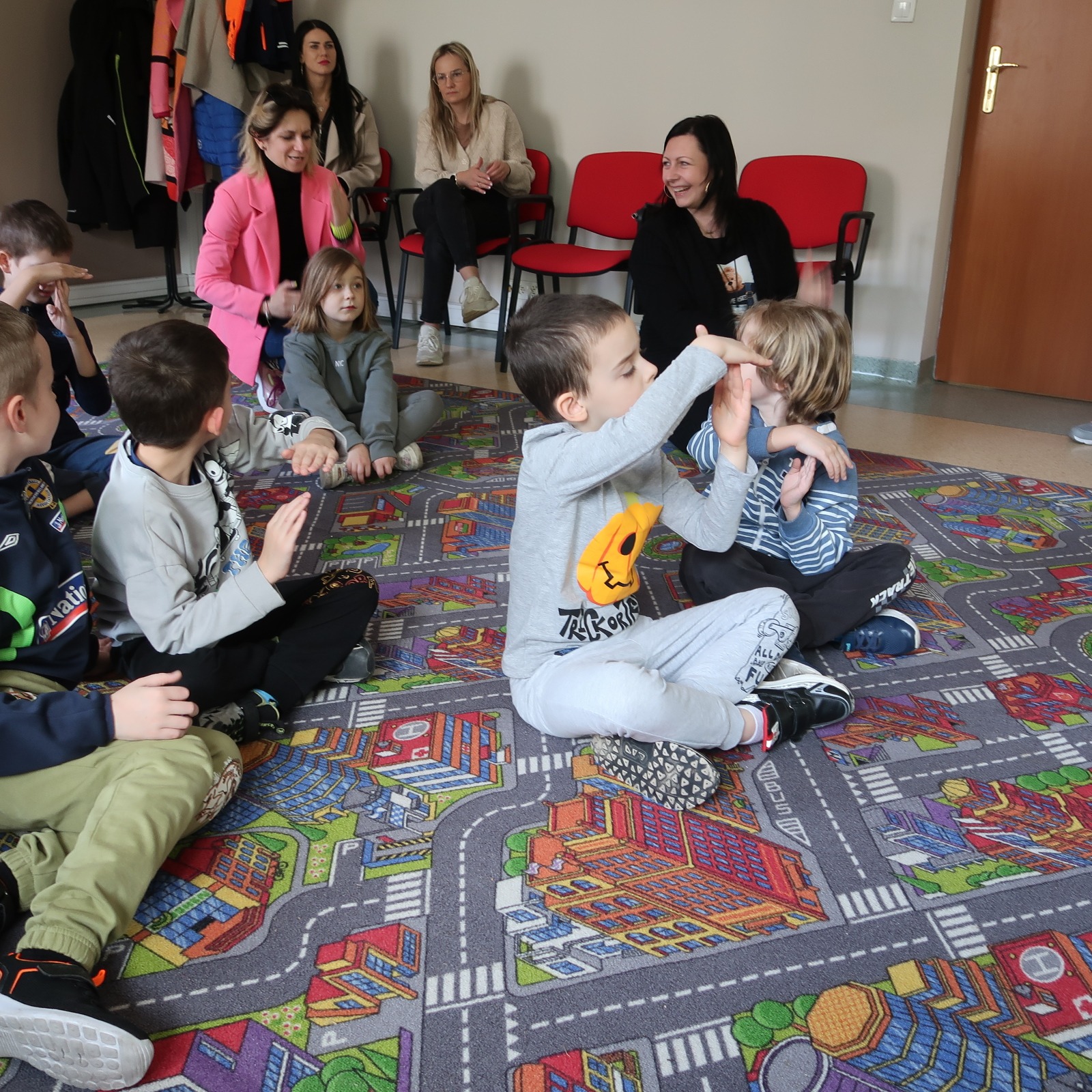 odwiedziny-PSP-12-4 Dzieci siedzą na dywanie i uważnie słuchają