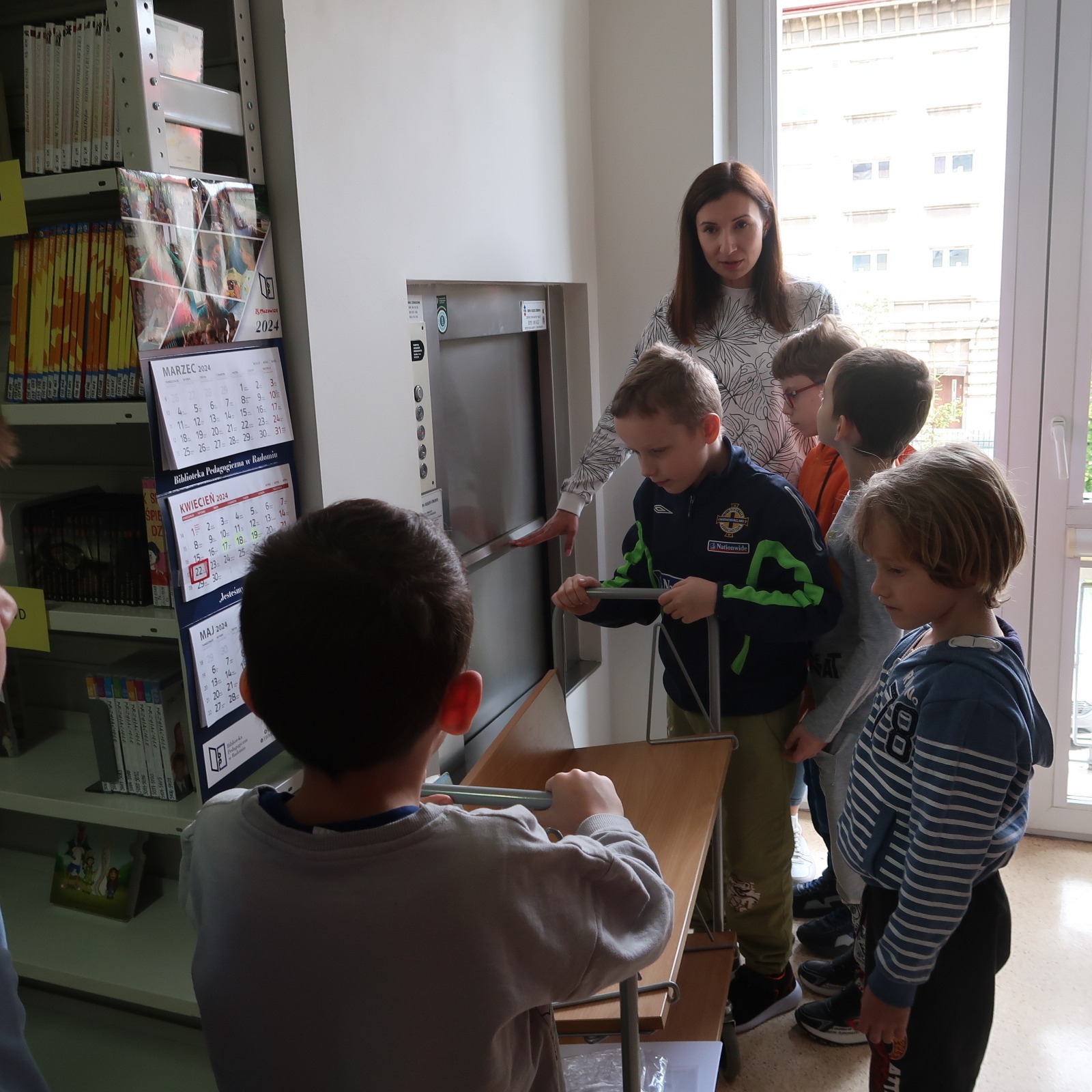 odwiedziny-PSP-12-5 Bibliotekarka pokazuje dzieciom windę towarową na książki
