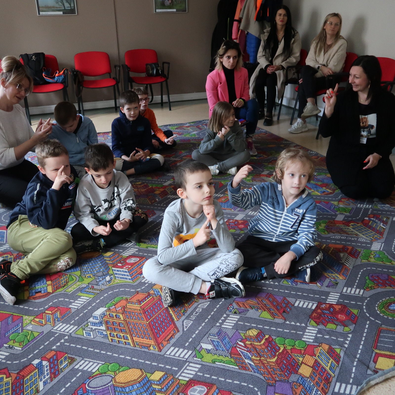 odwiedziny-PSP-12-6 Dzieci siedząc na dywanie słuchają nauczycielki