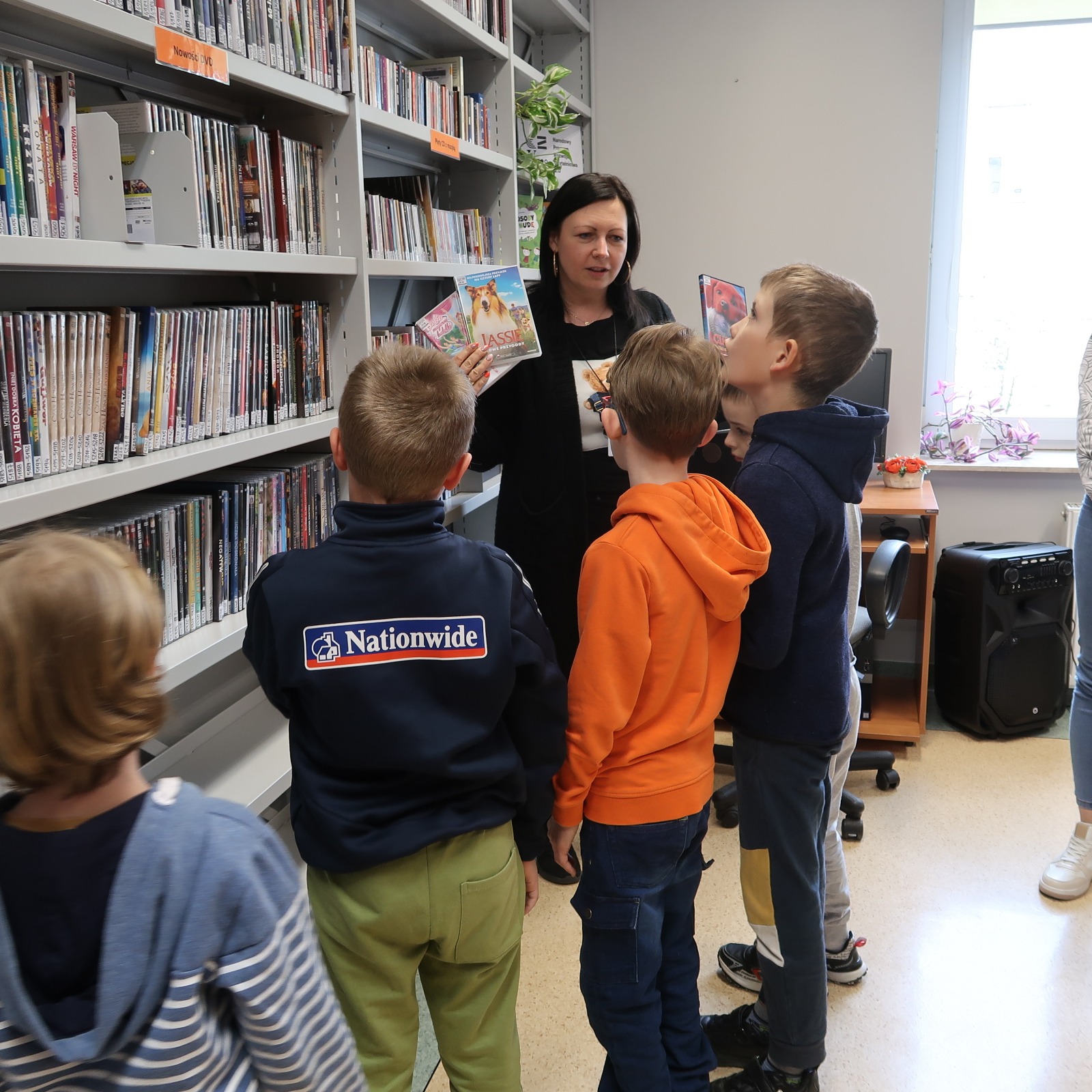 odwiedziny-PSP-12-7 Nauczycielka prezentuje dzieciom okładki filmów DVD dla dzieci i młodzieży