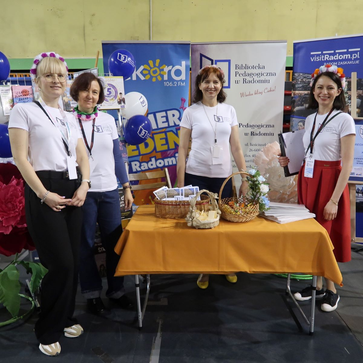 Cztery kobiety w jednolitych białych koszulkach prezentują ofertę edukacyjną Biblioteki Pedagogicznej w Radomiu