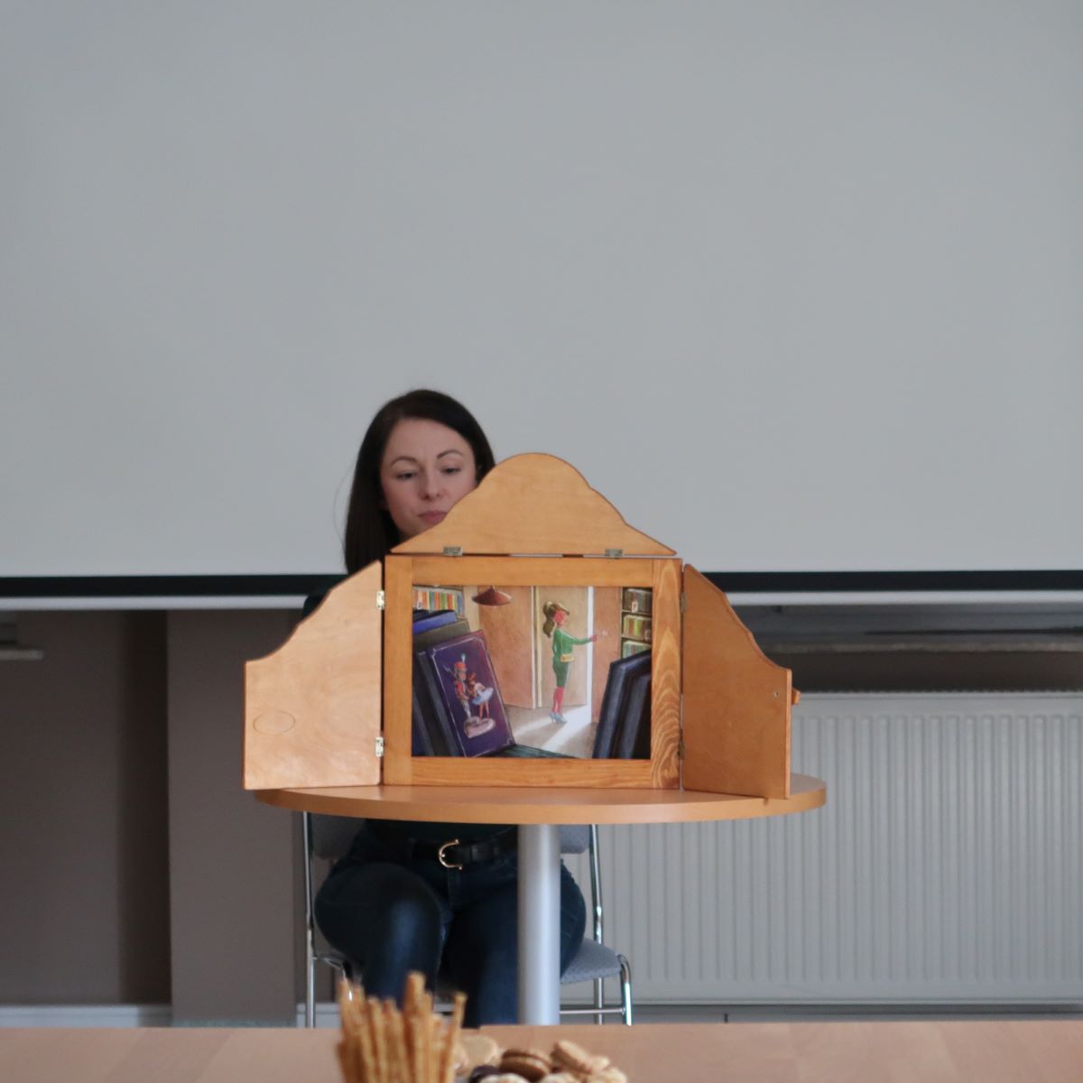 Młoda kobieta prezentuje scenę teatrzyku kamishibai