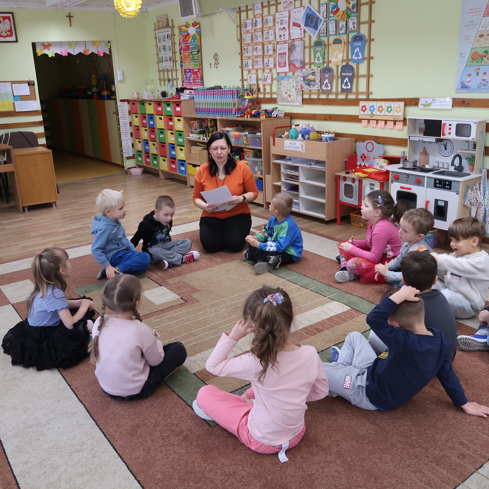 zajecia-PSP-12-1 Dzieci siedząc na dywanie uważnie słuchają nauczycielki