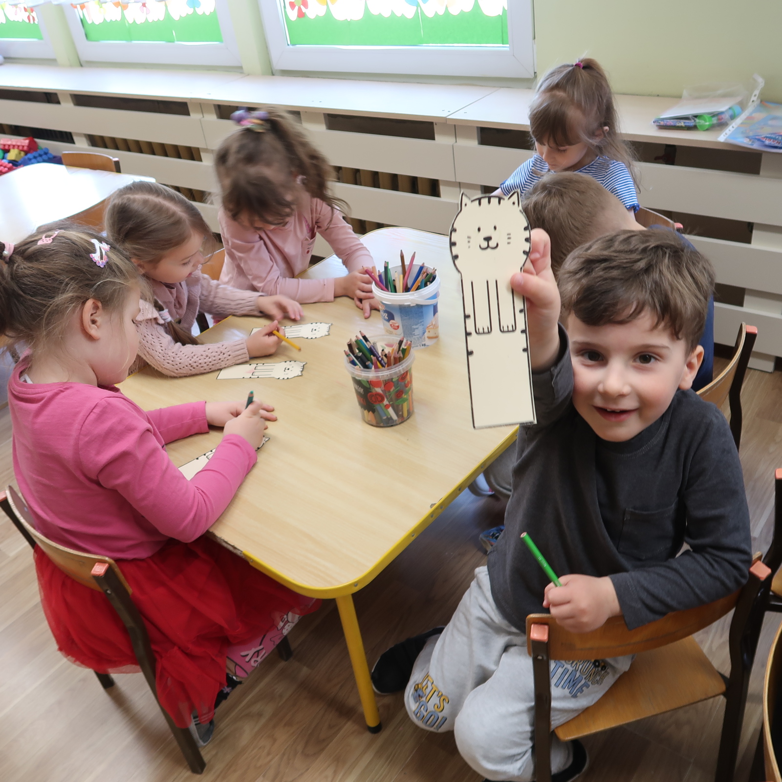 zajecia-PSP-12-5 Grupa dzieci wykonuje zakładki do książek siedząc przy stoliku