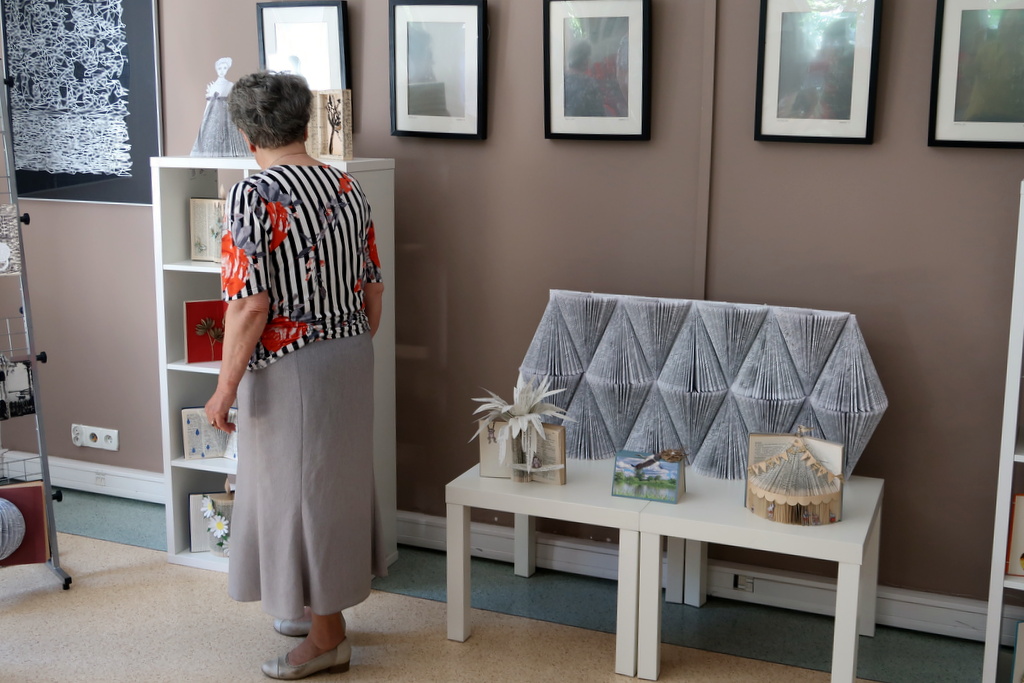 Starsza pani ogląda wystawę biblioteczną