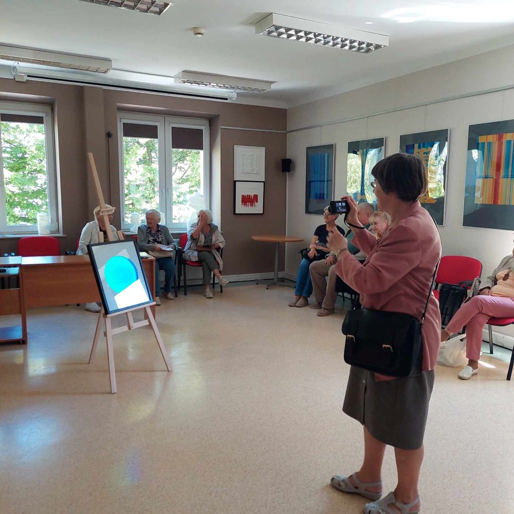 Starsza kobieta fotografuje pracę plastyczną