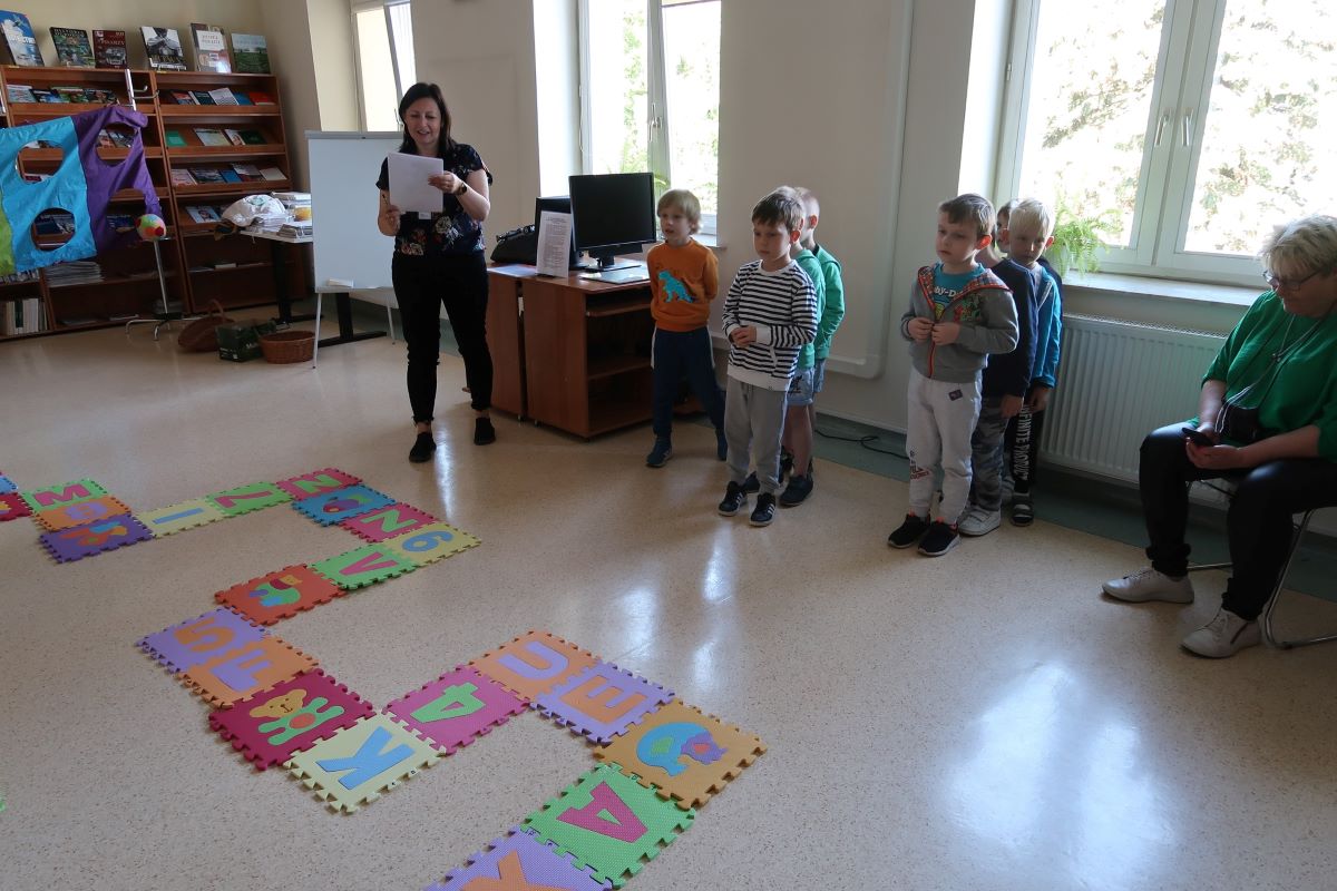 Dzieci przyglądają się kwadratom, na których narysowane są litery i wizerunki zwierząt.