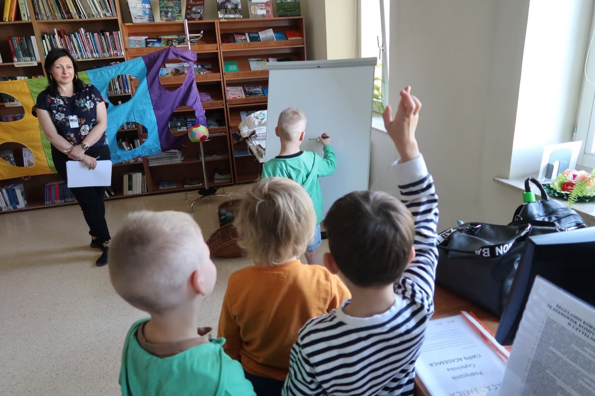 Mały chłopiec rysuje na dużej kartce papieru odwrócony