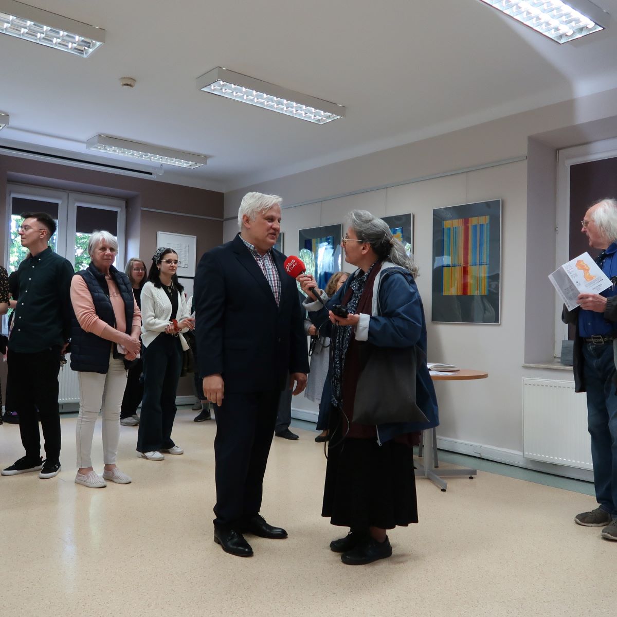 wystawa-noga-5 Kobieta z mikrofonem w ręku prowadzi wywiad ze starszym panem w garniturze