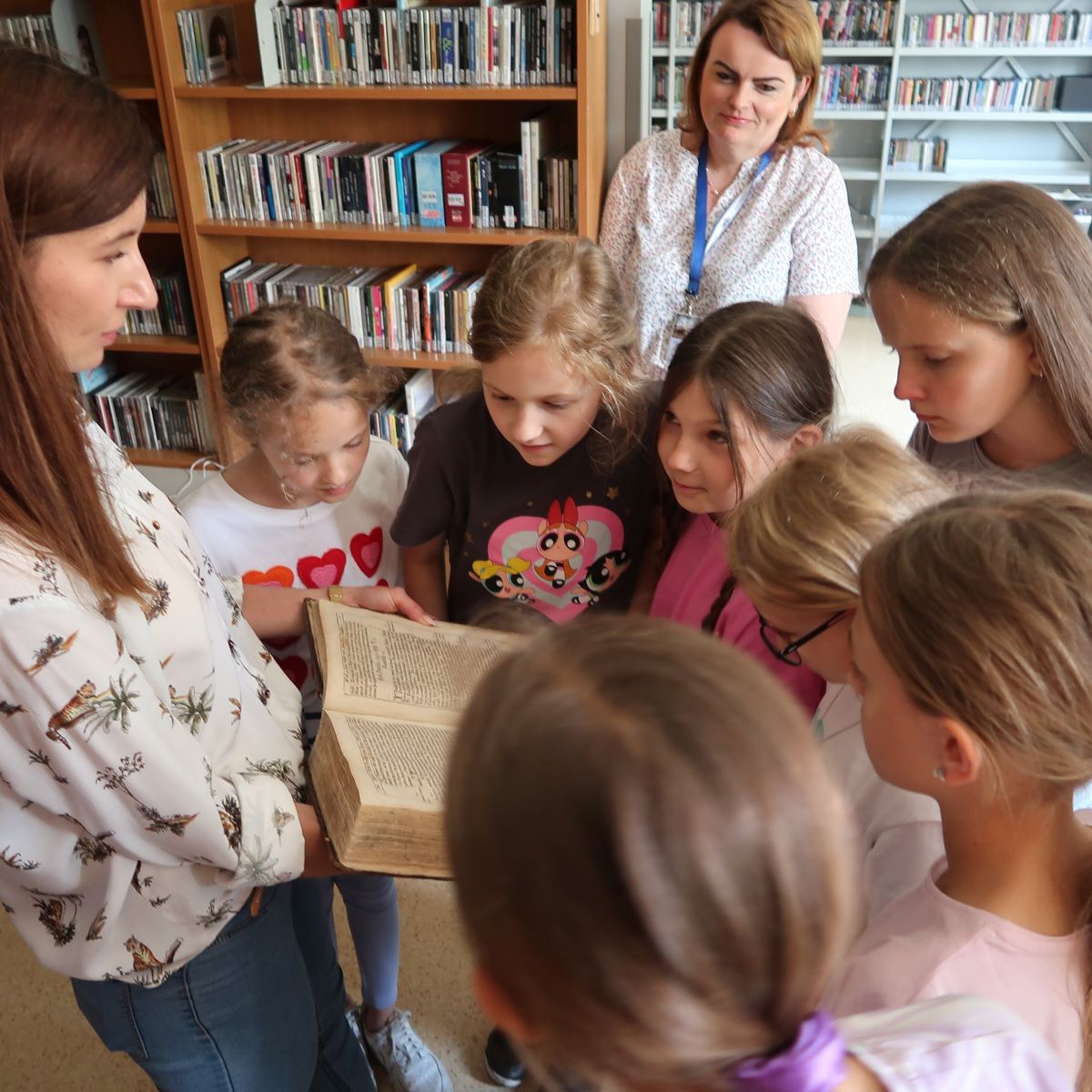Młoda kobieta pokazuje dzieciom bardzo stara książkę