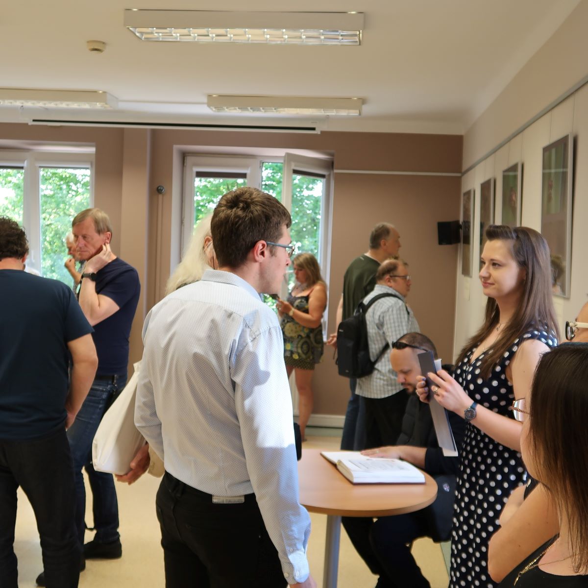 Grupa osób prowadzi ze sobą rozmowę w sali wystawowej