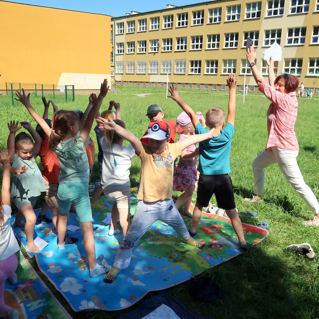 Dzieci powtarzają ćwiczenia fizyczne pokazywane przez nauczycielkę