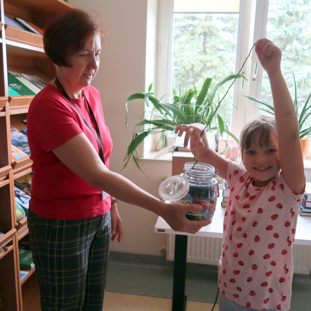kolorowypotwor-4 Mała dziewczynka z szerokim uśmiechem wyciąga długą nić ze słoika