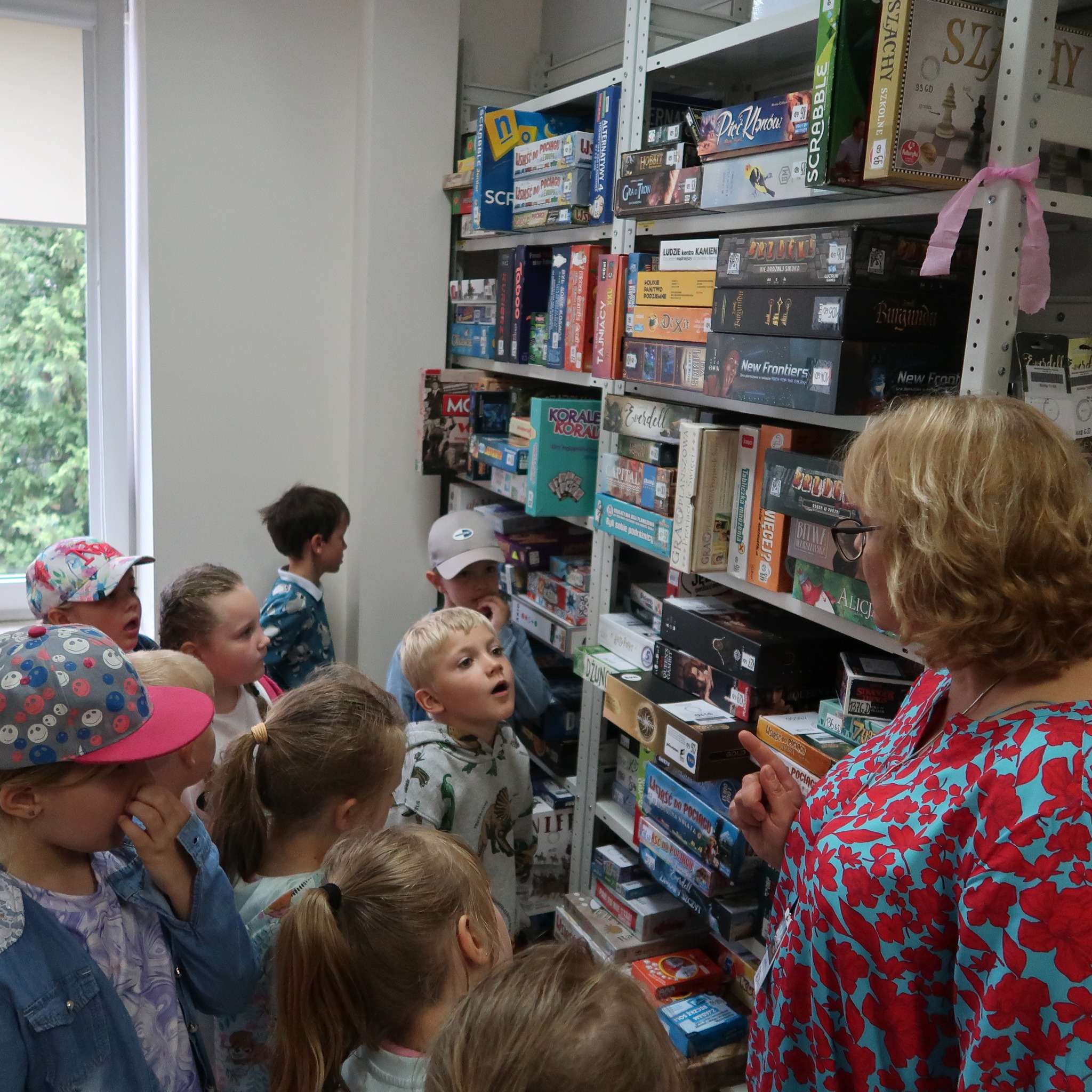 Dzieci stoją przy regale z grami planszowymi