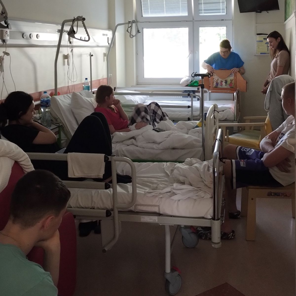 Dzieci z oddziału szpitalnego słuchają bajki w formie teatrzyku kamishibai.