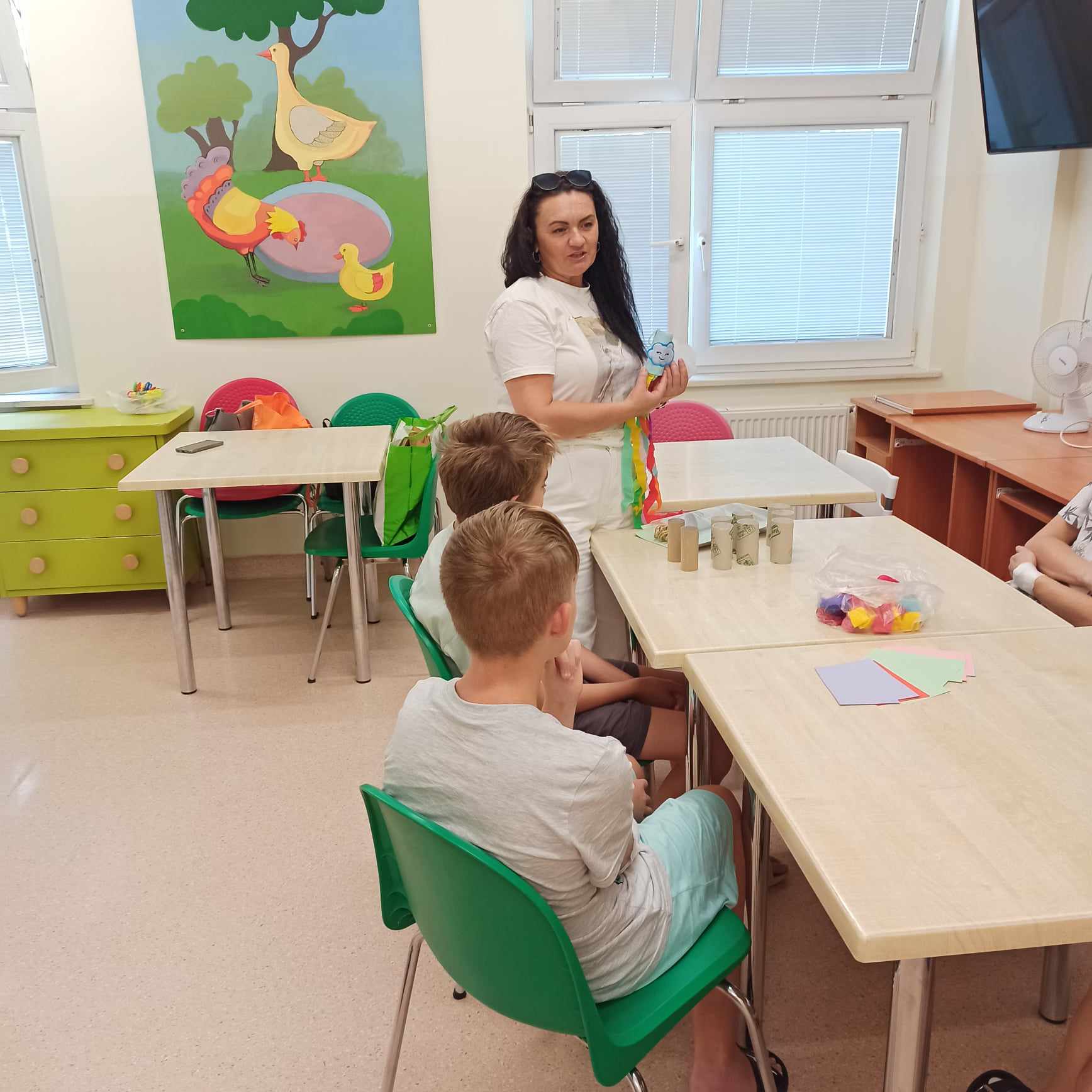 Prowadząca zajęcia pokazuje dzieciom sposób wykonania ozdób