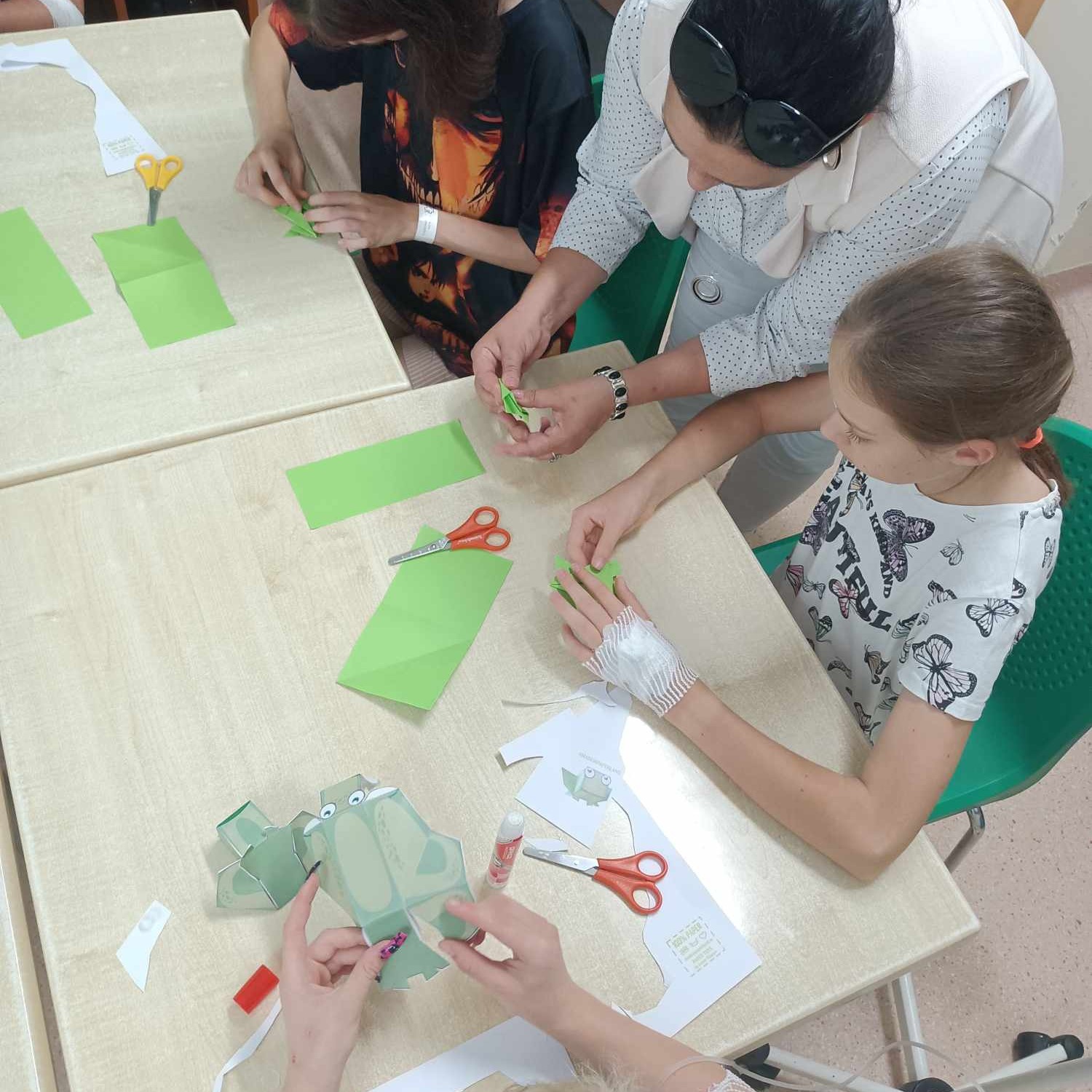 Dzieci wykonują prace plastyczne pod kierunkiem prowadzącej.