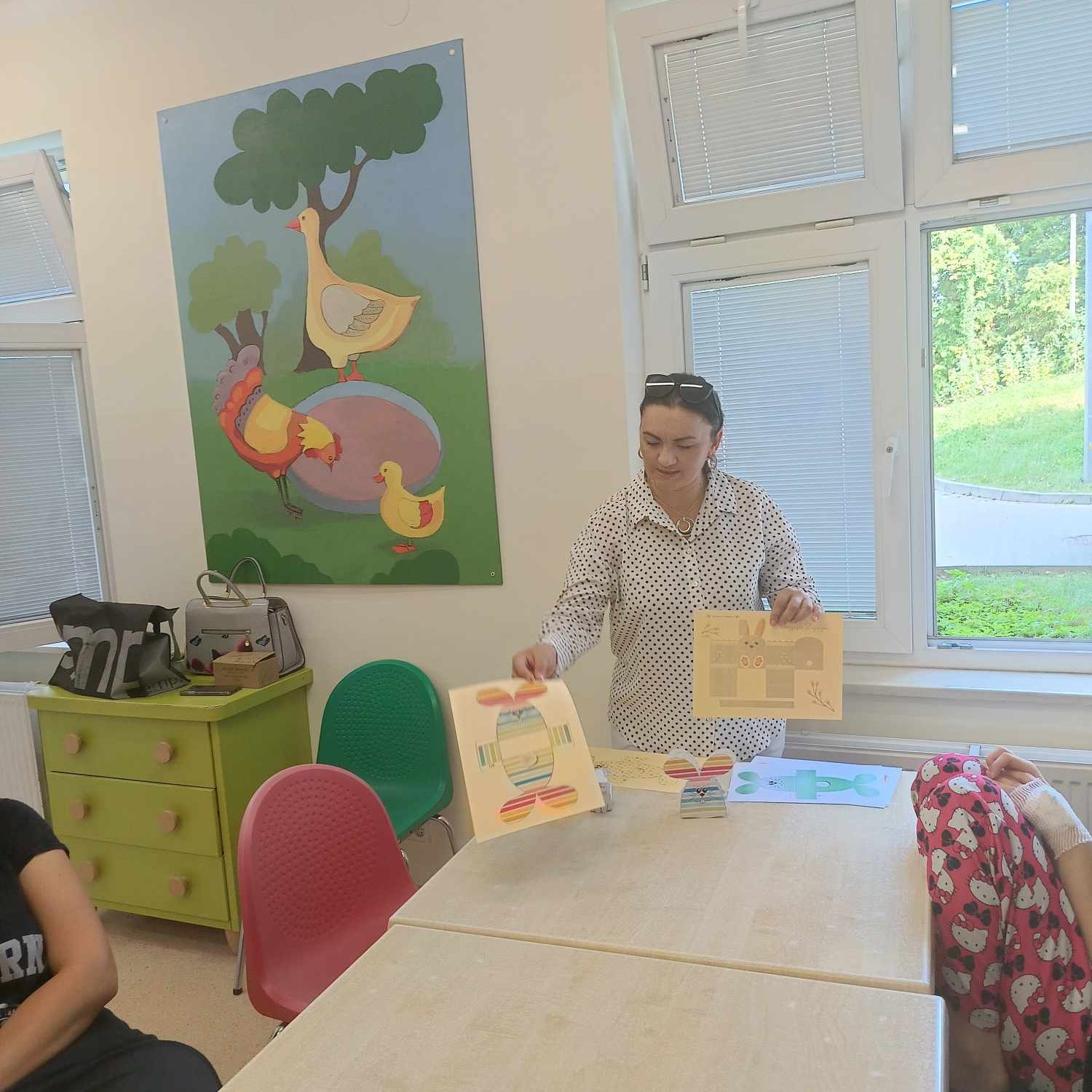 Kobieta pokazuje dzieciom szablony króliczków do wyklejenia