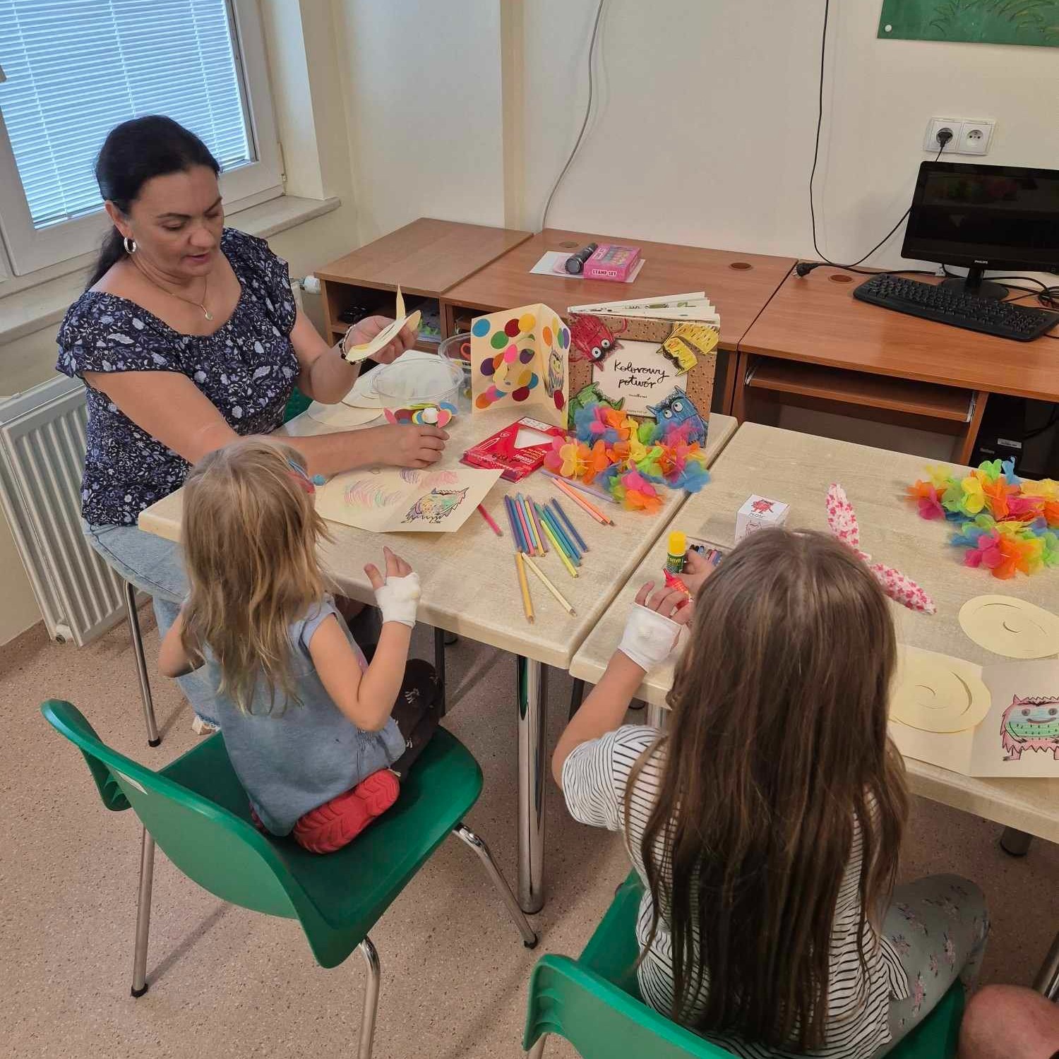 Pani pokazuje dzieciom ilustrację kolorowego potwora z książki