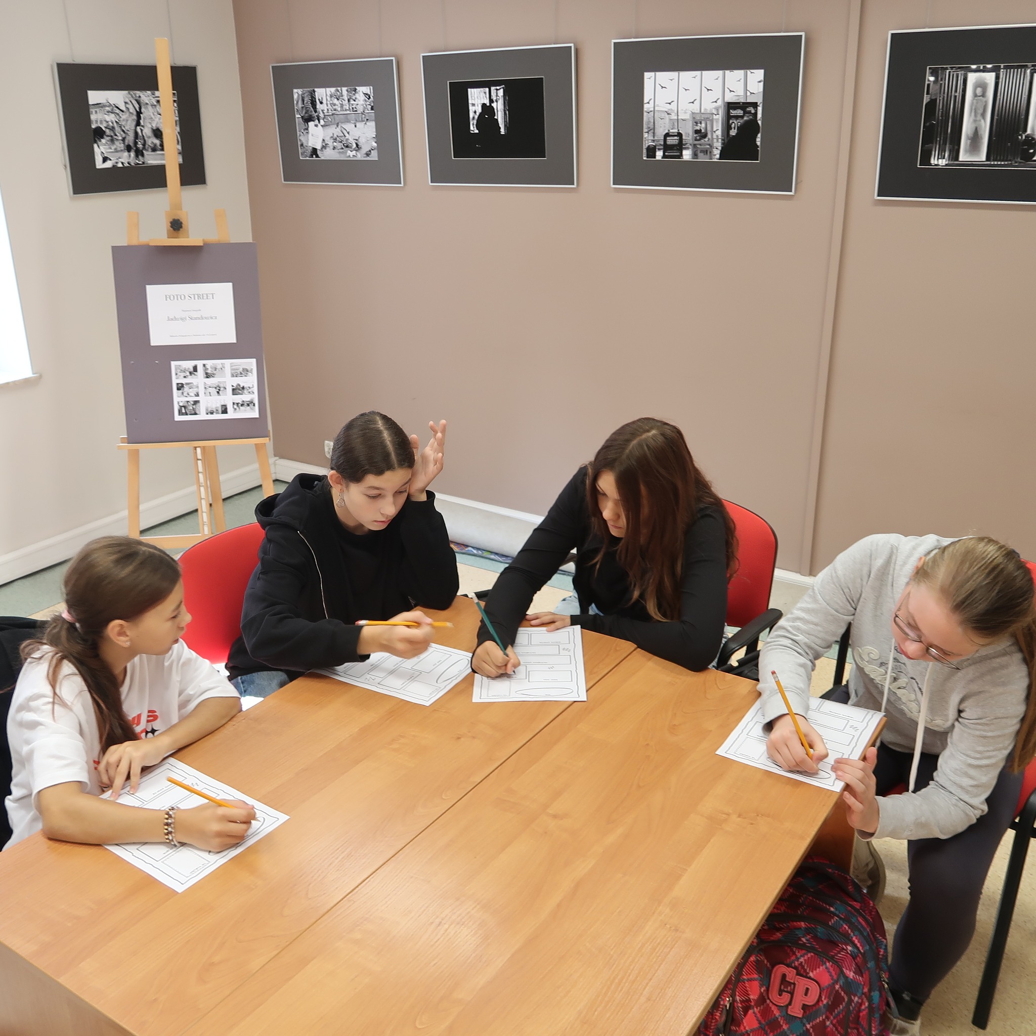 Cztery dziewczynki w skupieniu udzielają pisemnej odpowiedzi