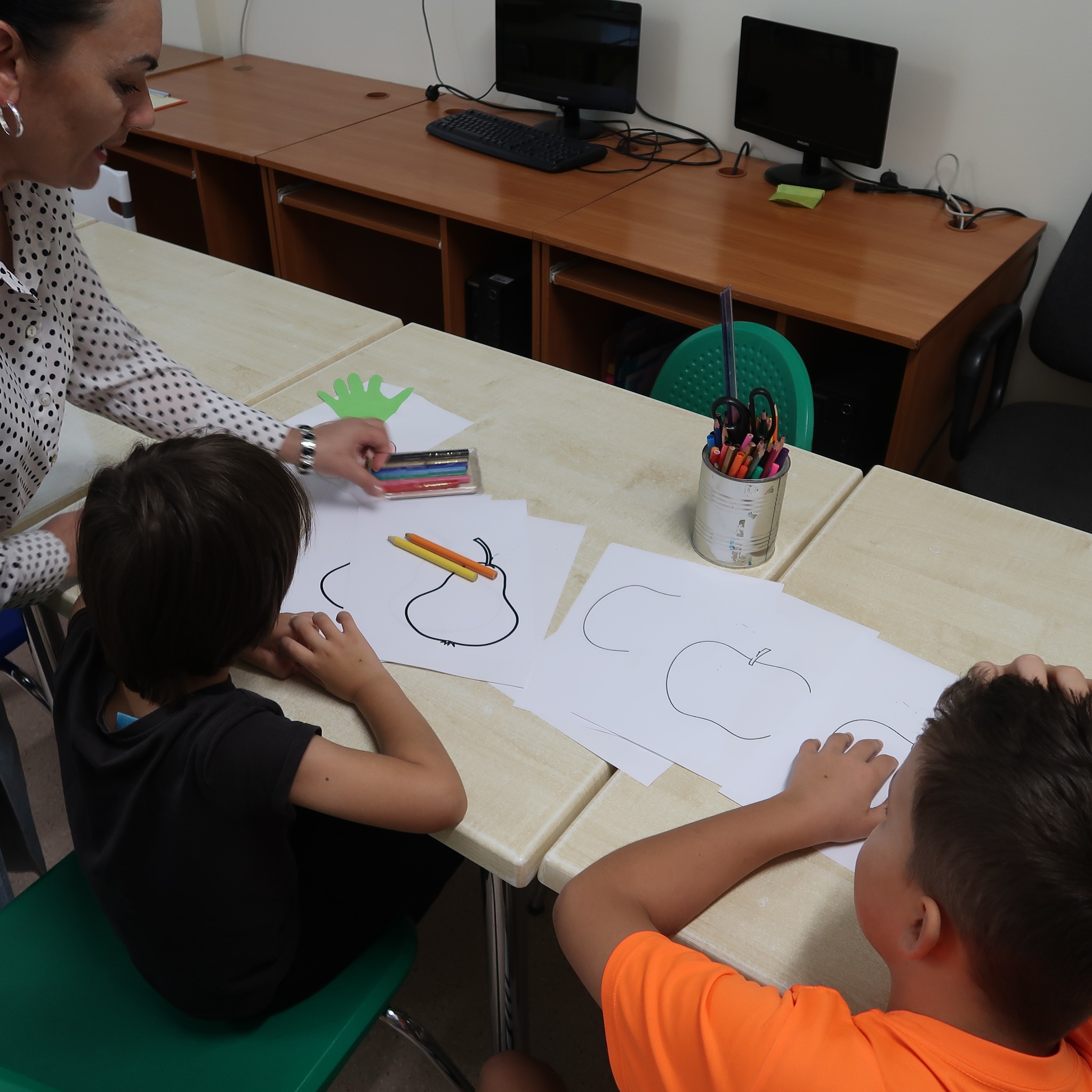 Pani rozdaje dzieciom rysowanki do kolorowania.