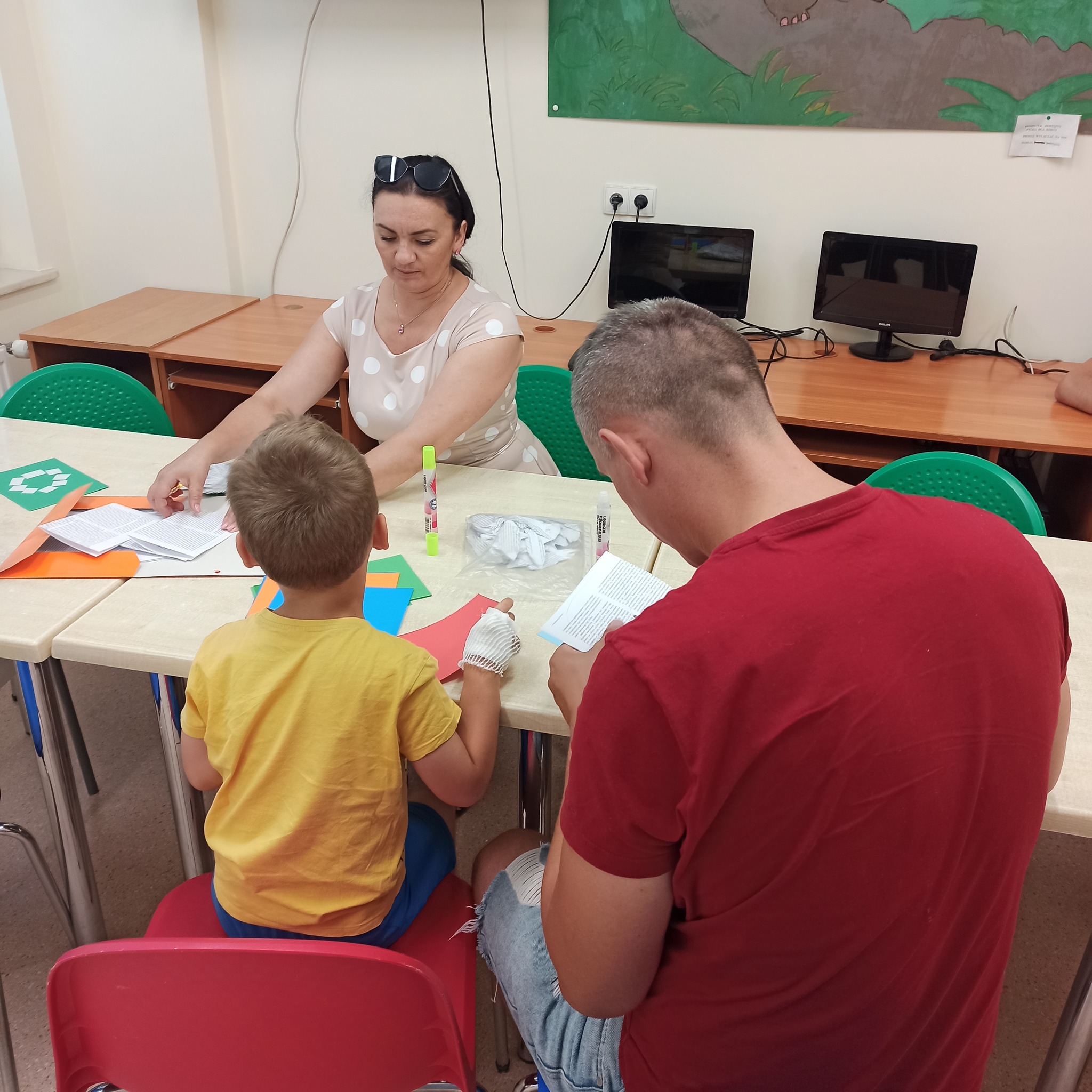 Mali pacjenci wykonują skrzydła z papieru po okiem pani.