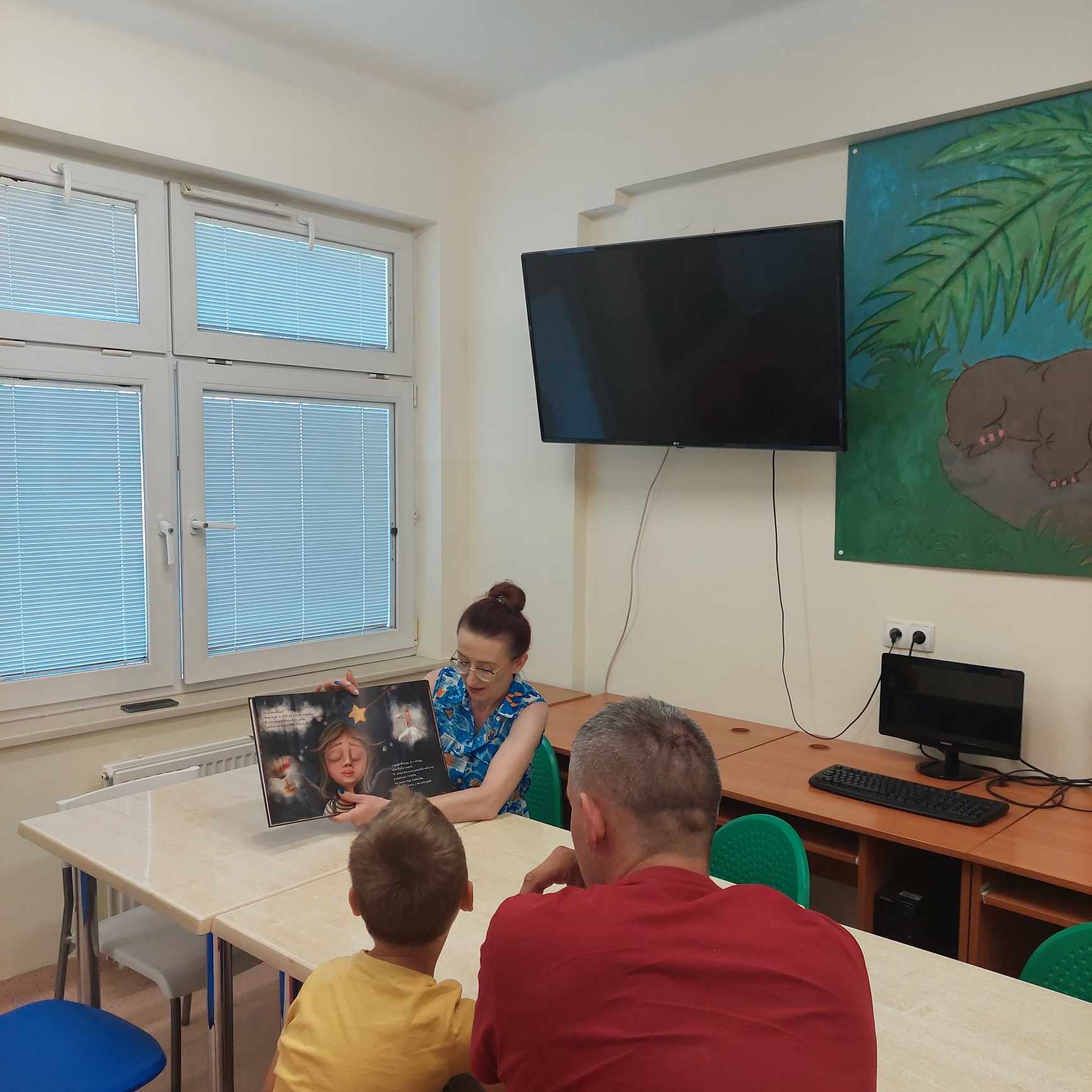 Prowadząca zajęcia pokazuje dzieciom obrazki z książki