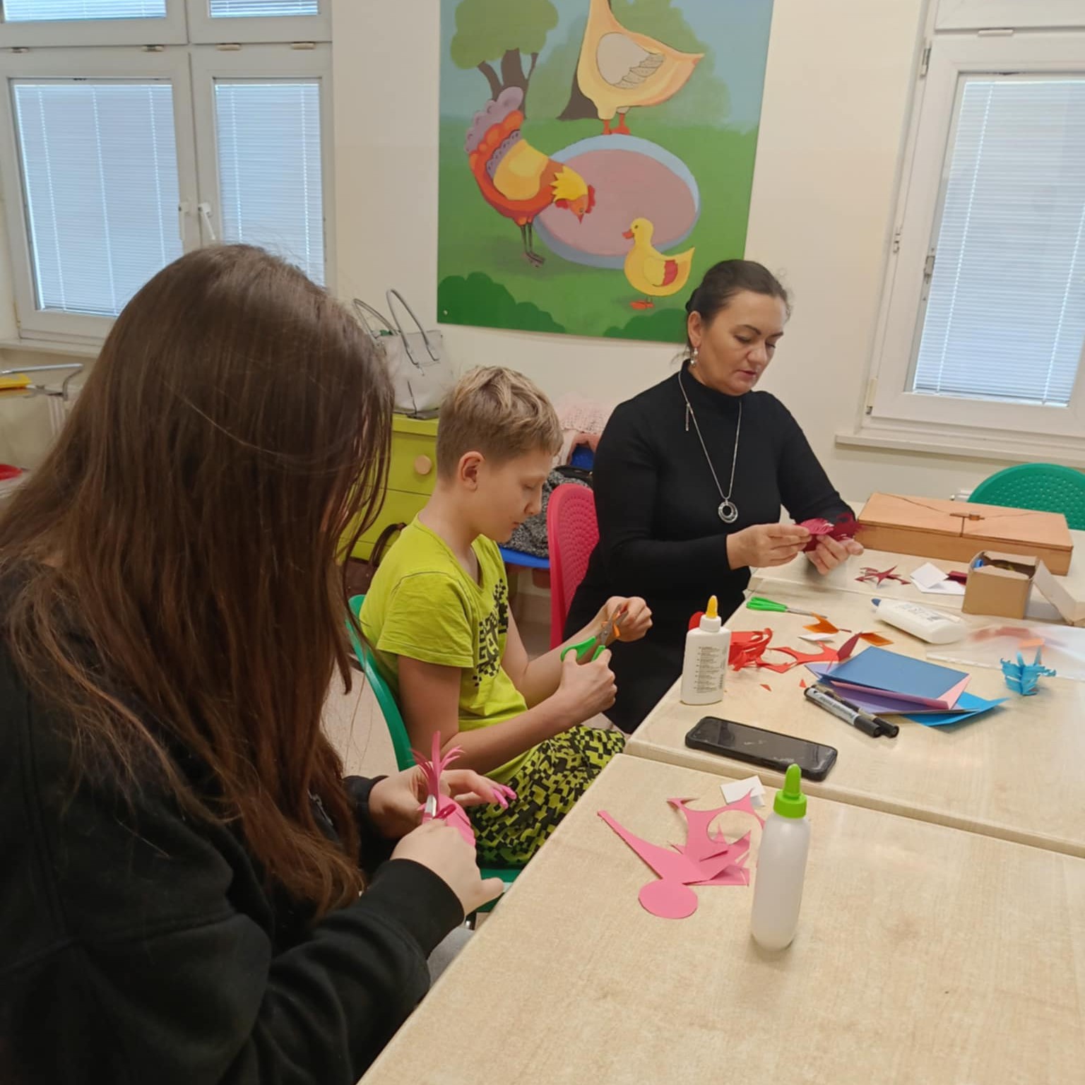 Dzieci pod kierunkiem pani wykonują prace plastyczne